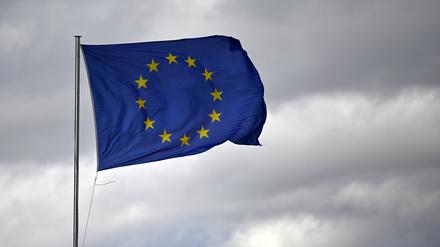 Eine EU-Flagge knattert im Wind vor bewölktem Himmel.
