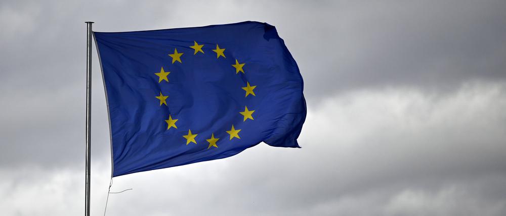Eine EU-Flagge knattert im Wind vor bewölktem Himmel.