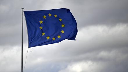 Eine EU-Flagge knattert im Wind vor bewölktem Himmel. 