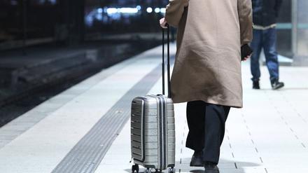 Eine Frau geht mit ihrem Reisekoffer auf einem Bahnsteig am Hauptbahnhof Hamburg entlang. 