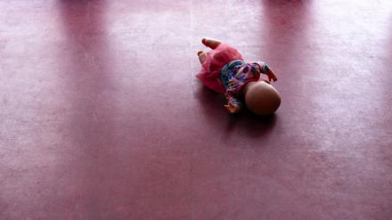 Eine Spielzeugpuppe liegt auf einem PVC-Fußboden. 