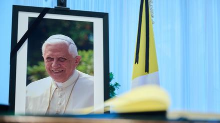 Das Kondolenzbuch für den verstorbenen emeritierten Papst Benedikt XVI. liegt auf einem Tisch vor einem Bild des Verstorbenen. 