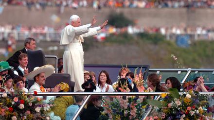 Der damalige Papst Benedikt XVI. grüßt von einem Schiff auf dem Rhein die Besucher des Weltjugendtages am Ufer in Köln. 