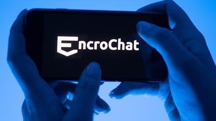 Eine Frau hält ein Smartphone mit dem Logo des Krypto-Messengerdienstes Encrochat.