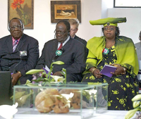 Opfer-Vertreter aus Namibia sitzen bei einer Berliner Trauerfeier im Jahr 2011 vor einem Schaukasten mit Schädeln.