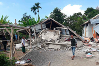 Bewohner gehen an Häusern vorbei, die durch ein Erdbeben beschädigt wurden.