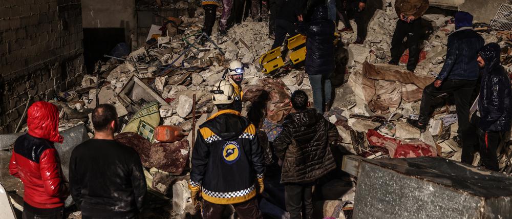 Syrische Zivilisten und Mitglieder der Weißhelme arbeiten an der Rettung von Menschen, die nach dem Erdbeben unter einem zerstörten Gebäude eingeschlossen sind. 