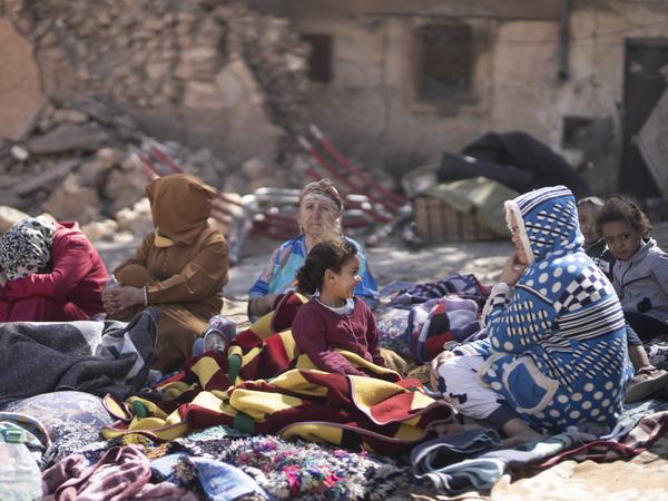 Familien sitzen in Marrakesch vor ihren zerstörten Häusern.