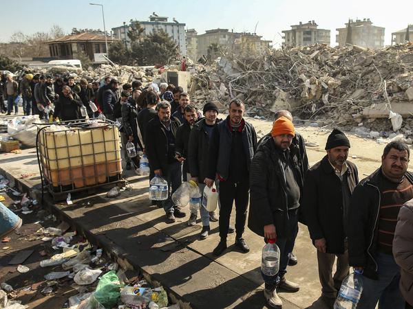 Menschen stehen in Kahramanmaras (Türkei) neben eingestürzten Gebäuden an, um Wasser zu holen.