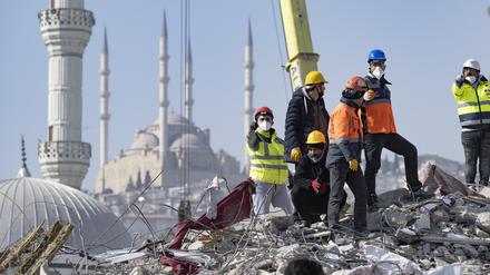 Helfer suchen in den Trümmern eines Wohnblocks in Kahramanmaras (Türkei) nach Verschütteten. 