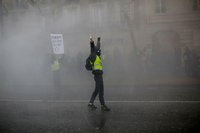 Ein vermummter Demonstrant der sogenannten "Gelbwesten" steht in dichtem Rauch von Rauchgranaten.