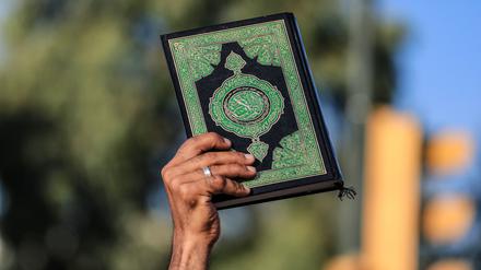 Ein Mann hält ein Exemplar des Koran während eines Protests. Nach der Verbrennung eines Korans in Schweden haben im Irak Hunderte Menschen demonstriert.