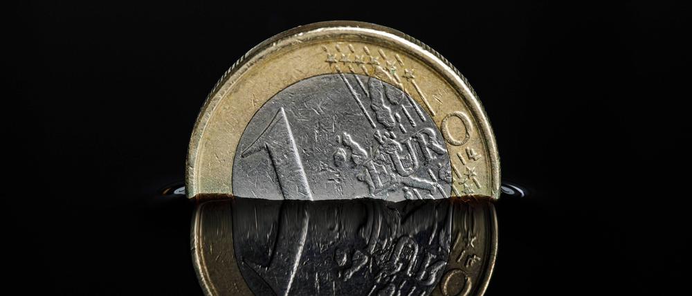 Euro-Münze in einer dunklen Flüssigkeit.