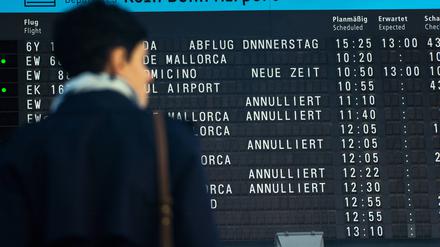 Eine Frau steht vor der Abfluginformationen am Abflugterminal des Flughafens Köln und Bonn (Archivbild)