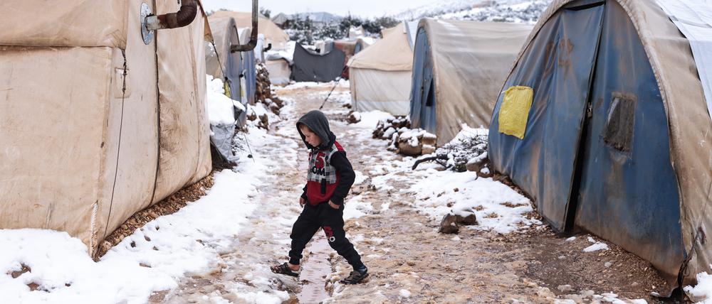 Ein Kind läuft zwischen Zelten in einem schneebedeckten Lager für Binnenvertriebene in der Nähe der Stadt Afrin.