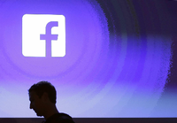 Mark Zuckerberg, Gründer von Facebook, geht am Firmensitz an einem leuchtenden Facebook logo vorbei.