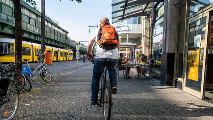 Fahrradfahrer fährt auf dem Gehweg auf der Schönhauser Allee in Berlin-Prenzlauer Berg.