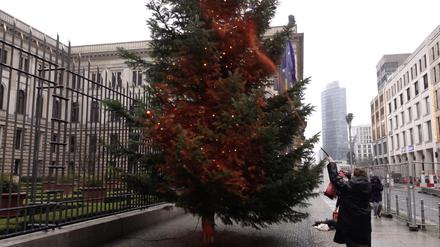Ein Mitglied der Klimaschutzgruppe „Letzte Generation“ besprüht einen Weihnachtsbaum vor dem Bundesrat mit orangener Farbe.