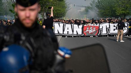 Auf Krawall gebürstet. Ein französischer Gendarm steht vor den Fans vom FC Nantes, die vor dem Spiel ein Transparent hochhalten.