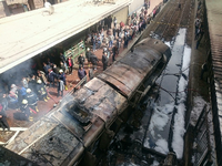 Rettungskräfte stehen neben einem ausgebrannten Waggon im Bahnhof in Kairo.