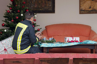 Ein Feuerwehrmann zündet während einer Vorführung in einem nachgebauten Wohnzimmer Kerzen an einem Adventskranz an.