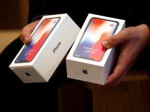 Ein Mann hält zwei Boxen für das iPhone X von Apple (Symbolbild).