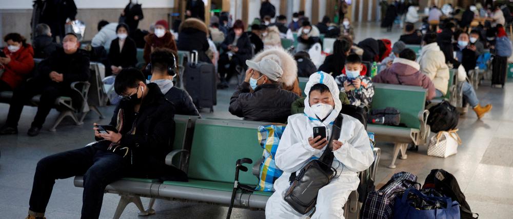 In Peking sitzt eine Person mit einem Schutzanzug. 