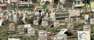 Ein Kind steht auf einem Friedhof im Jemen.