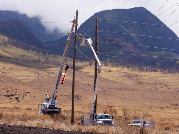 Elektriker reparieren Stromleitungen, die in die vom Feuer verwüstete Stadt Lahaina auf der Insel Maui führen.