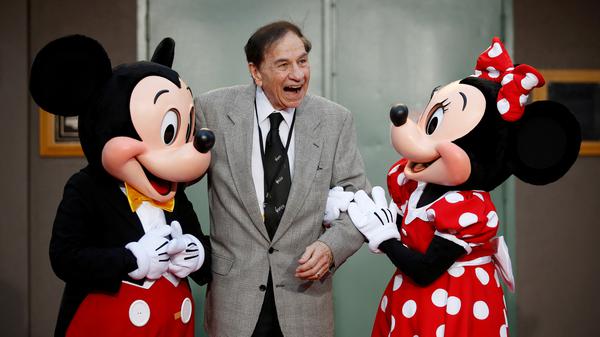 Der Songwriter Richard M. Sherman posiert mit Micky und Minnie Maus.
