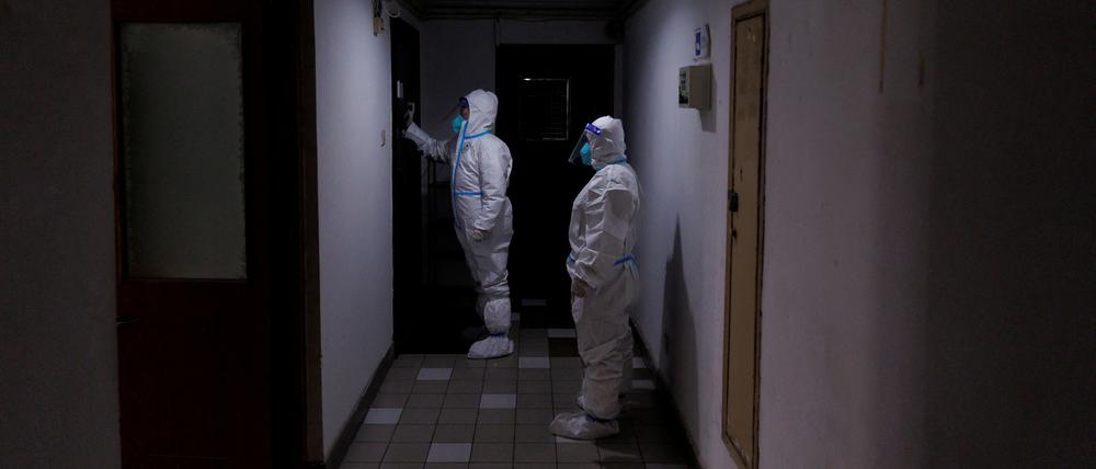 Mitarbeiter der Gesundheitsbehörden kontrollieren in Peking Apartments, die im Lockdown sind.  