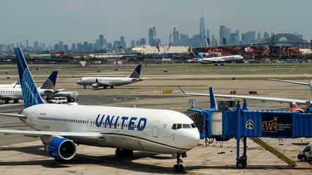 Das One World Trace Center und die New Yorker Skyline sind zu sehen, während Flugzeuge der United Airlines auf dem Rollfeld des Newark Liberty International Airport in Newark landen. 
