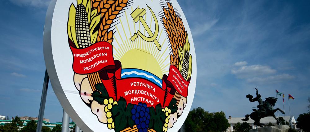 Eine Frau geht an einem riesigen Wappen von Transnistrien vorbei.