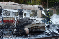 Ein Feuerwehrmann löscht die Flammen im ausgebrannten Zug.