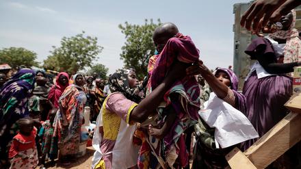 Mitarbeiterinnen des Roten Kreuzes helfen einem sudanesischen Kind in einen Truck: Mit seiner Familie musste das Kind aus der Darfur Region fliehen.