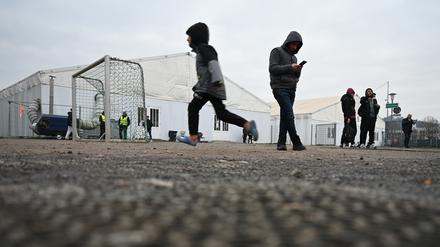 Flüchtlinge halten sich auf dem Gelände einer Flüchtlingsunterkunft vor den Zelten auf. 