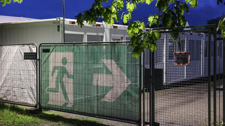 Ein Transparent mit dem Symbol für den Fluchtweg hängt vor Wohncontainer der kommunalen Erstaufnahmeeinrichtung in Köln-Zollstock. 