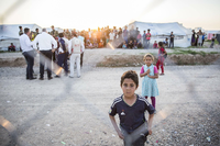 Kinder stehen hinter dem Zaun eines Flüchtlingslagers im Irak.