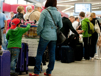 Passagiere warten mit ihrem Gepäck an einem Check-in-Schalter im Flughafen Tegel (Symbolbild).