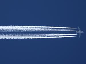  Ein Flugzeug der Qatar Airline hinterlässt am wolkenlosen Himmel Kondensstreifen.