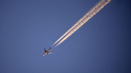 Flugzeug mit Kondensstreifen am blauen Himmel. 