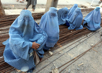 In Burkas gekleidete Frauen sitzen in Herat (Afghanistan) auf Metallstangen.