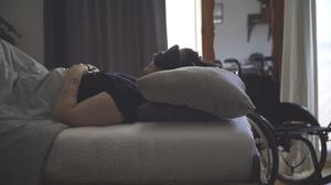 Eine Frau mit ME/CFS liegt mit Schlafmaske in einem abgedunkelten Zimmer. (Symbolbild)