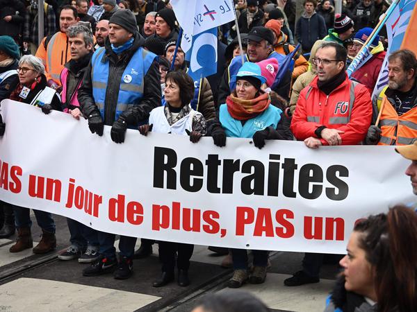 Protestierende in Frankreich halten einen Banner: „Pansion, nicht einen Tag länger“. 
