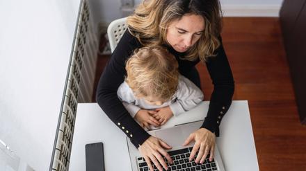 Mit Kleinkind hinterm Laptop? Selbstständige müssen oft früher in den Beruf zurückkehren als abhängig Beschäftigte.
