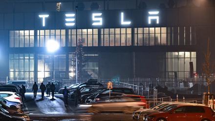 Brandenburg, Grünheide: Mitarbeiter gehen am frühen Morgen auf einem Parkplatz zum Werk des US-Elektroautobauers Tesla. 