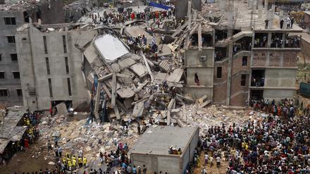 Rettungskräfte stehen auf den Resten einer  zusammengestürzten Fabrik in Bangladesh. Bei dem Einsturz des Gebäudes am 24. April 2013 kamen mehr als 1100 Menschen ums Leben. 