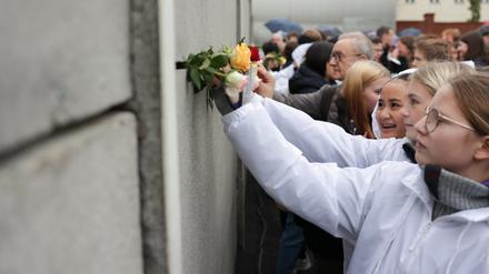 Schüler aus Deutschland, Frankreich und Norwegen steckten bei der zentralen Gedenkfeier zum 33. Jahrestag des Mauerfalls in der Gedenkstätte Berliner Mauer Rosen in die sogenannte Vorderlandmauer. 