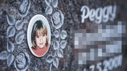 Ein Gedenkstein mit dem Porträt des Mädchens Peggy auf einem Friedhof.