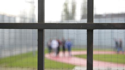 Hinter einem Gitter laufen Gefängnisinsassen der Justizvollzugsanstalt Stuttgart-Stammheim über einen Gefängnishof. 